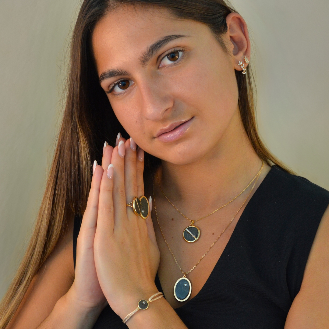 Collier plaquée or avec pendentif rond intérieur en pyrite (noire) avec un trait esthétique brillant dans son diamètre. Bijou porté, Crédit GEMITY.