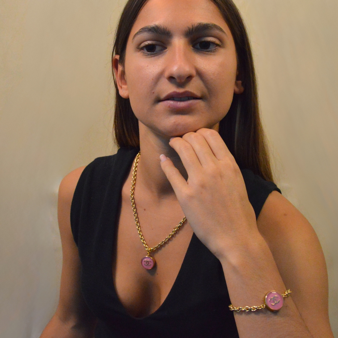 Upcycling d’un bouton rose d’une maison de luxe monté sur une chaîne de grosses mailles (5 mm) d’une longueur maximum de 20 cm. Bijou seul, Crédit GEMITY. Upcycling d’un bouton rose d’une maison de luxe monté sur une chaîne de grosses mailles (5 mm) d’une longueur maximum de 20 cm. Bijou porté, Crédit GEMITY.