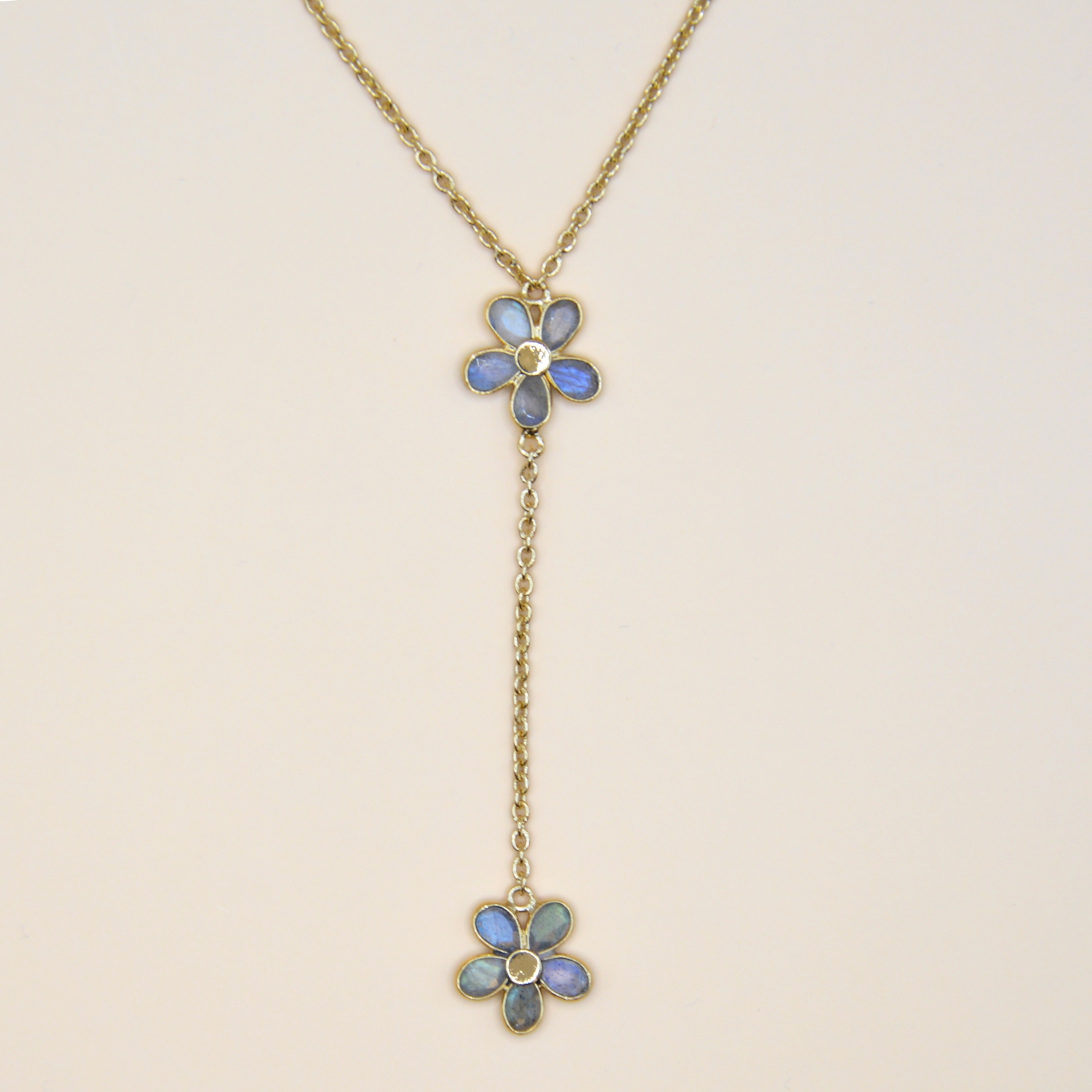 Collier en plaqué or 3 microns onré de 4 fleur délicates, cahcunes composée de pétales en labradorite, ce bijou évoque à la fois la grâce et la féminité. La chaîne fine souligne la disposition subtile des fleurs, avec un design qui tombe dans le décolleté et met celui ci en valeur. Florila apporte une touche moderne et sophistiquée. Bijou seul, Crédit GEMITY