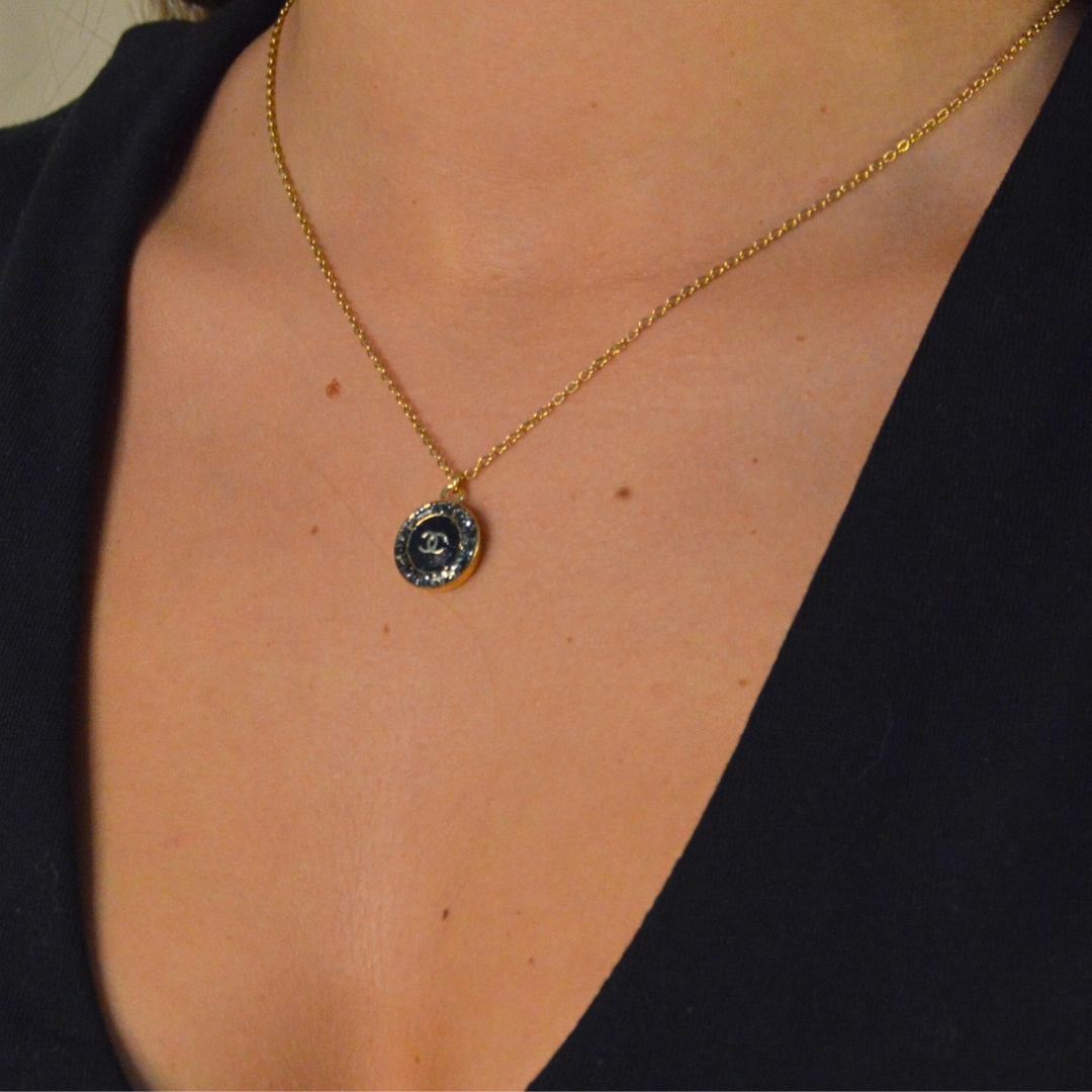 Upcycling d’un bouton noir à strass d’une maison de luxe monté en pendentif sur une chaîne de mailles fines (2 mm) d’une longueur de 50 cm. Bijou seul, Crédit GEMITY. Upcycling d’un bouton noir à strass d’une maison de luxe monté en pendentif sur une chaîne de mailles fines (2 mm) d’une longueur de 50 cm. Bijou porté, Crédit GEMITY.