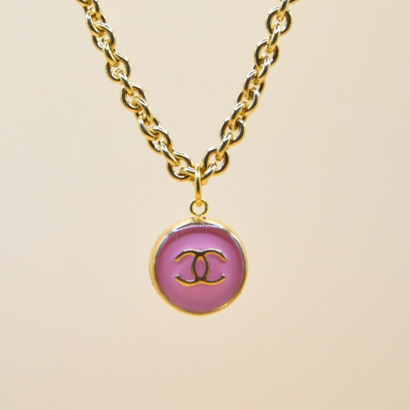 Upcycling d’un bouton rose d’une maison de luxe monté en pendentif sur une chaîne de mailles épaisses (5 mm) d’une longueur de 50 cm. Bijou seul, Crédit GEMITY. Upcycling d’un bouton rose d’une maison de luxe monté en pendentif sur une chaîne de mailles épaisses (5 mm) d’une longueur de 50 cm