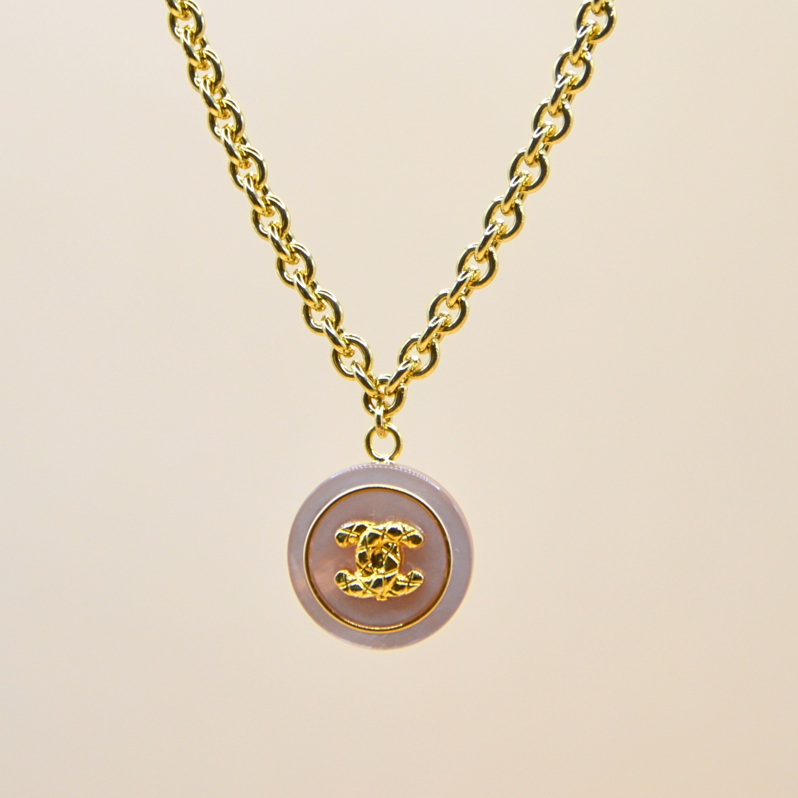 Upcycling d’un bouton rose nacré d’une maison de luxe monté en pendentif fixe sur une chaîne de mailles intermédiaires (4 mm) d’une longueur de 40 cm. Bijou seul, Crédit GEMITY