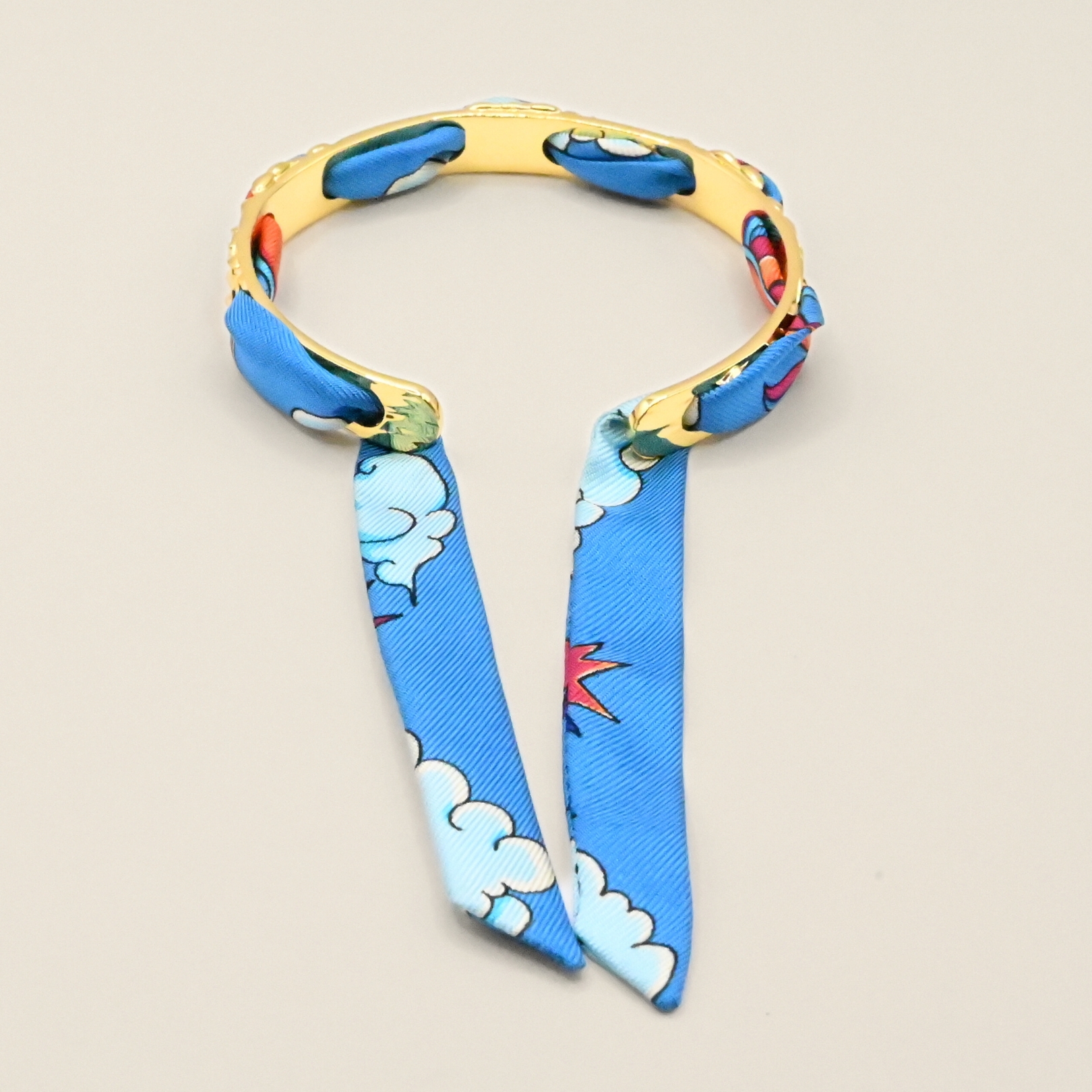 Le bracelet FÉERIE est un des intemporels les plus appréciés de la marque, pour celles qui recherchent le raffinement et la discrétion. C'est le bracelet le plus fin de nos créations (0,8 cm de largeur), travaillé de petites lianes et feuilles, il est à la fois très élégant et poétique. Ce bracelet est accompagné du ruban cirque des rêves coloré. Bijou seul, Crédit GEMITY