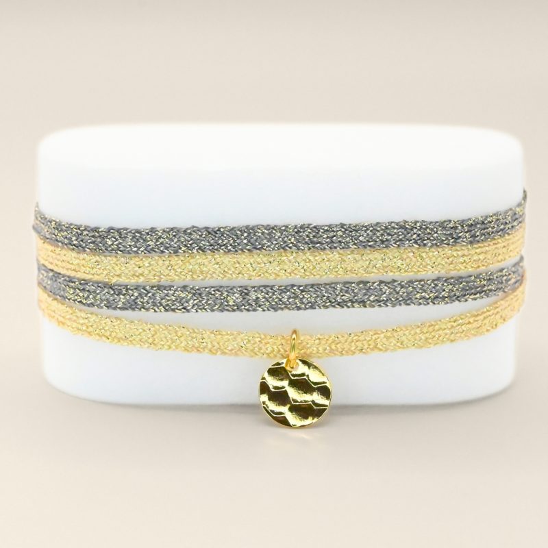 "Bracelet double tours en tissu de deux coloris différents avec une pastille martelée dorée à l’or fin. Fermoir en plaqué or réglable . Bijou seul, Crédit GEMITY"