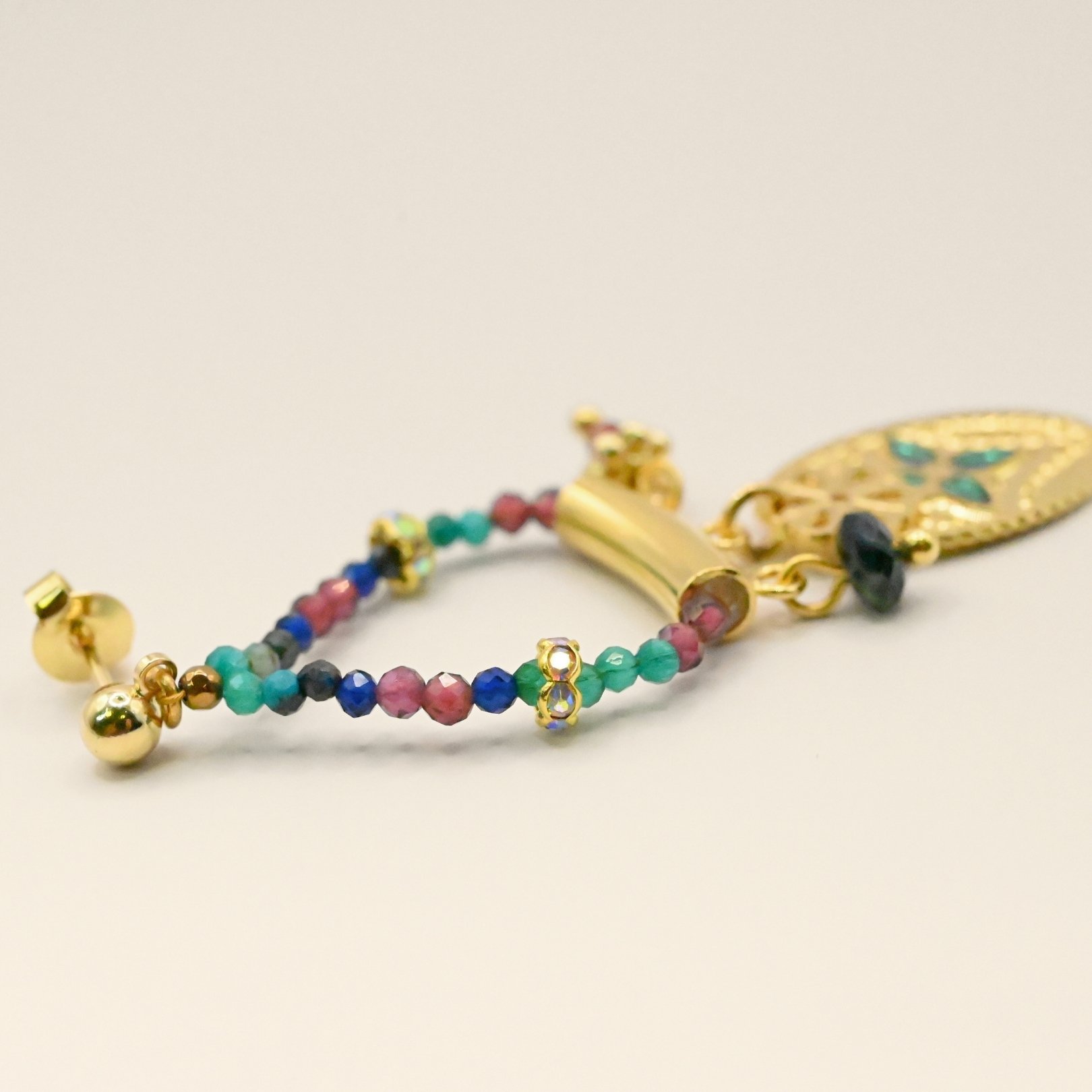 Ces boucles d’oreilles sont un véritable hommage à l’art indien. Chaque pièce est façonnée et émaillée à la main, mettant en valeur le savoir-faire traditionnel. Les pendentifs ovales évoquent des éléments floraux tels que le lotus, symbole porte-bonheur. Bijou seul, Crédit GEMITY