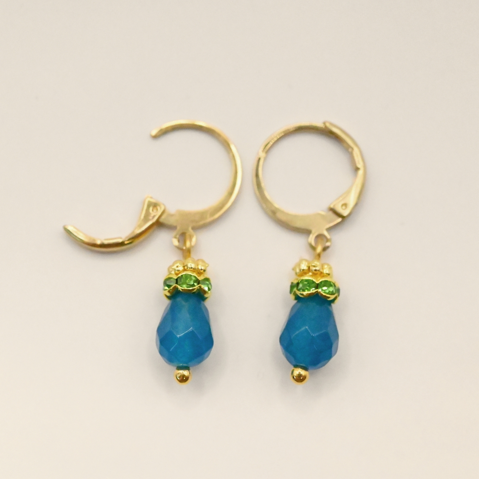 Petites boucles d'oreille parfaites pour le quotidien ou pour être portées en association avec le collier Jaipur par exemple. Elles sont très légères et d'une couleur éclatante. Un anneau strassé vient faire le pont entre la goutte et un petit anneau doré orné de mini boules typiquement indien. Bijou seul, Crédit GEMITY