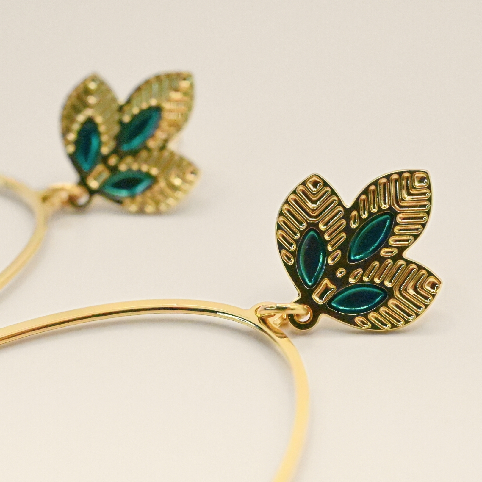 Grandes créoles épurées tout en légèreté. Les 3 feuilles viennent habiller gracieusement votre lobbe et donner une pointe de couleur. Les motifs sur le bas de la boucle donnent à l'ensemble le caractère Indien. Bijou seul, Crédit GEMITY