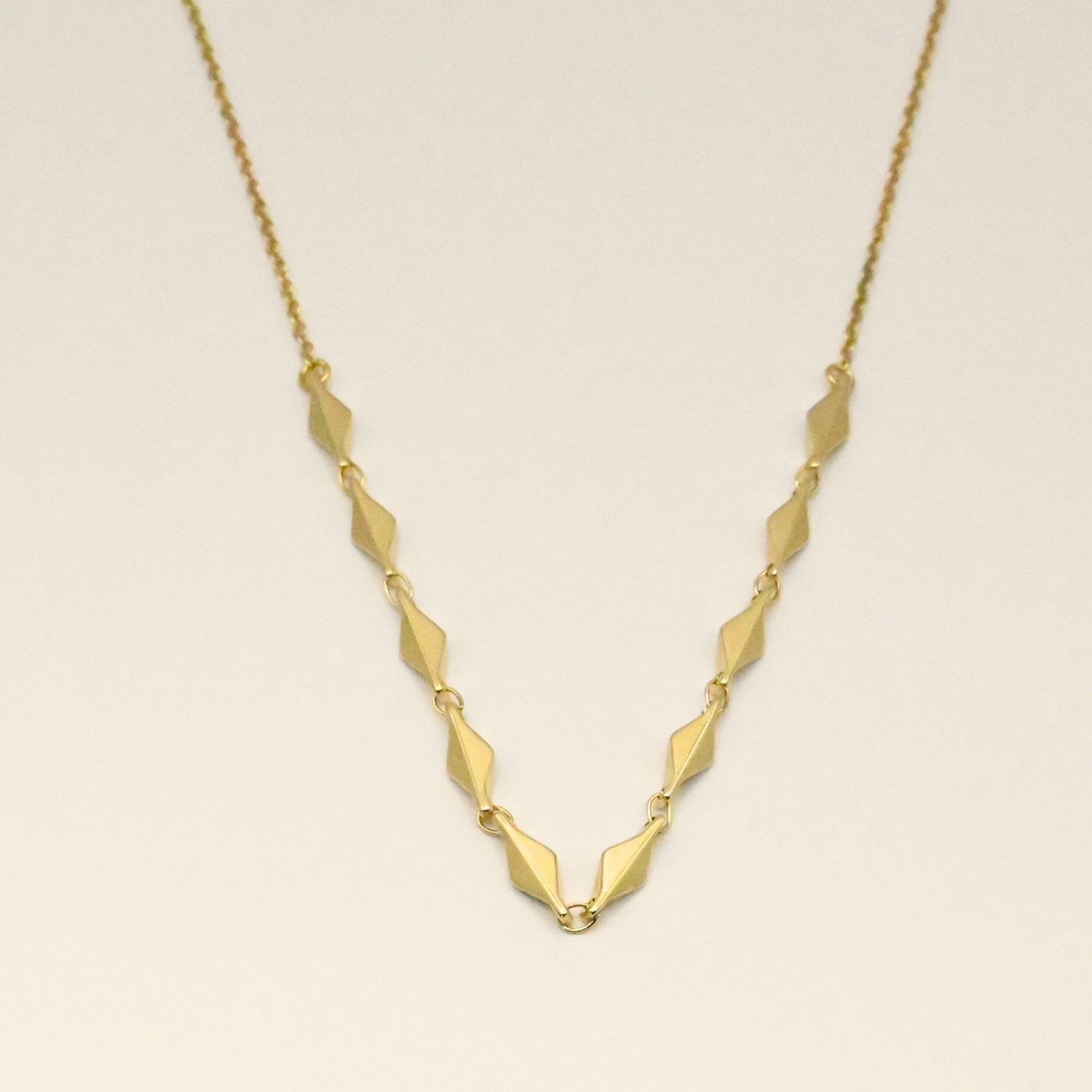 Magnifique collier doré composé de petits losanges en relief. Bijou seul, Crédit GEMITY