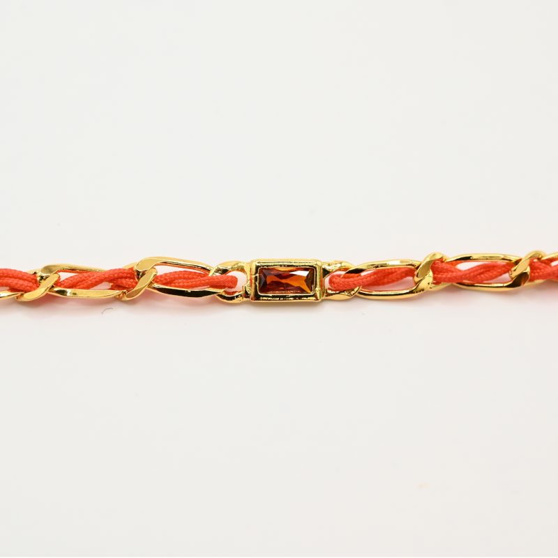 "Bracelet avec un cordon doré et un gemme transparent en son centre. Composition : 100% plaqué or. Contient 1 strass coloré transparent. . Bijou seul, Crédit GEMITY"