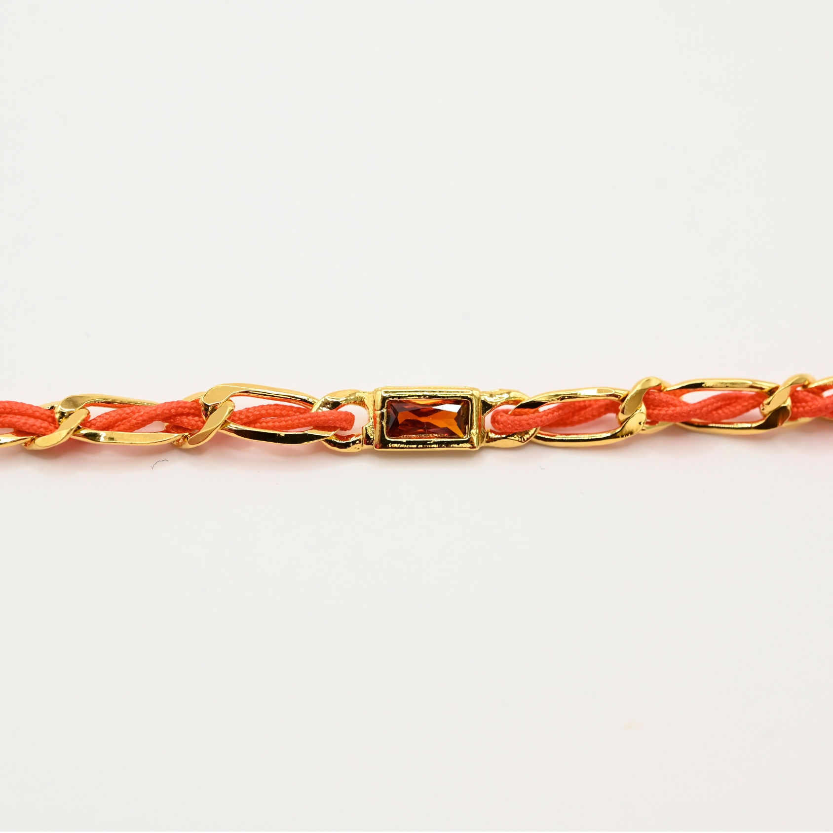 "Bracelet avec un cordon doré et un gemme transparent en son centre. Composition : 100% plaqué or. Contient 1 strass coloré transparent. . Bijou seul, Crédit GEMITY"