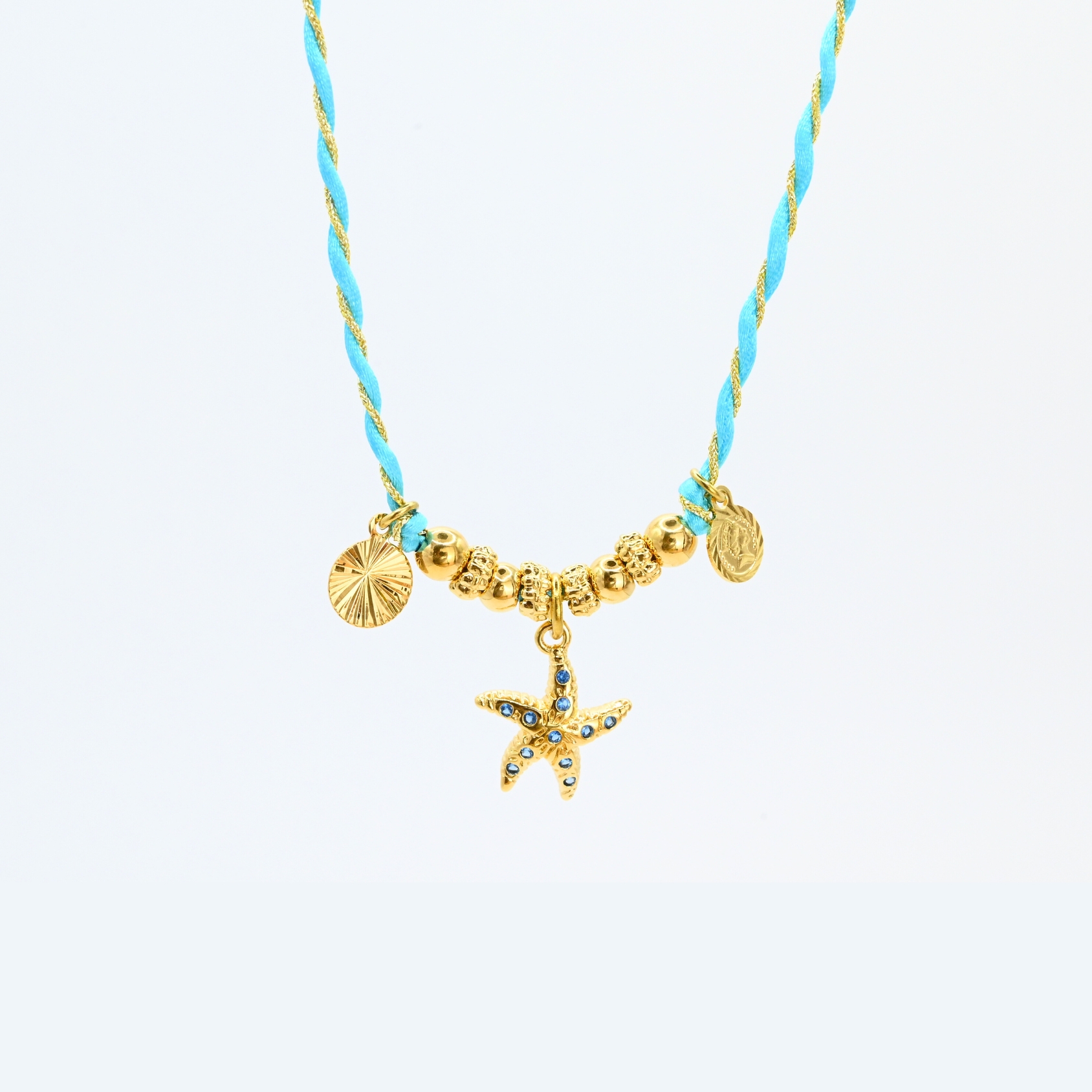"L’élégance décontractée de la côte basque. Ce bracelet mêle fils de coton torsadé, touches dorées et couleurs vibrantes, pour une alliance parfaite entre raffinement et fraîcheur de l’océan. Orné d'un charm, il incarne une harmonie bohème et sophistiquée à porter au quotidien. Composition : Plaqué or et fils de coton torsadés. . Bijou seul, Crédit GEMITY"
