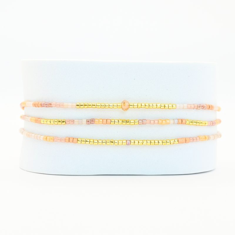 ce bracelet fin à 3 rangs combine des perles dorées, nude et dans les tons rosés pour un design doux et féminin. L'un des rangs est orné d'une plus grande perle au centre, apportant une touche de sophistication et de brillance. . Bijou seul, Crédit GEMITY
