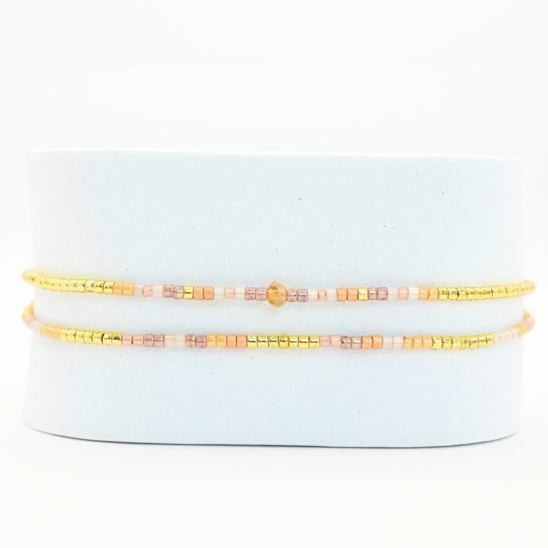 ce bracelet fin à 2 rangs associe des perles dorées, blanches, roses et nude pour un design doux et coloré. L'un des rangs est orné d’une perle plus grosse au centre, apportant une touche de sophistication à ce bijou délicat. . Bijou seul, Crédit GEMITY