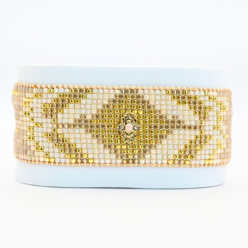 ajoutez une touche de sophistication à votre poignet avec cette grande manchette composée de 15 rangs de perles dorées et nude. Ce bijou élégant est sublimé par un ornement doré au centre, créant une harmonie parfaite entre luxe et simplicité.. Bijou seul, Crédit GEMITY