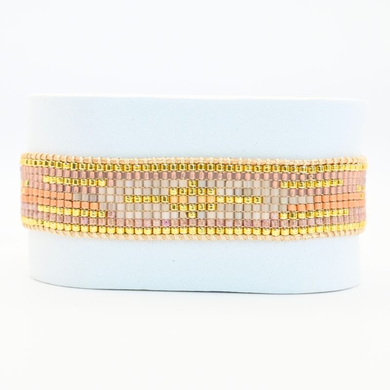 cette manchette élégante et sophistiquée se compose de 9 rangs de perles nude et dorées, créant un équilibre subtil entre douceur et éclat. Un motif central blanc apporte une touche lumineuse et raffinée. . Bijou seul, Crédit GEMITY