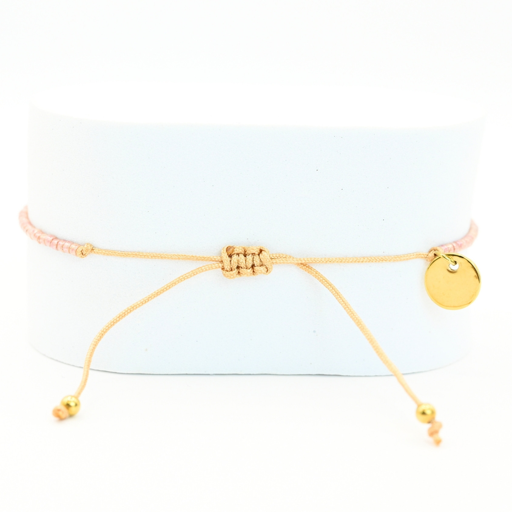 " ce bracelet délicat allie finesse et élégance avec son cordon ajustable et ses perles dorées et rose poudré. . Bijou seul, Crédit GEMITY"