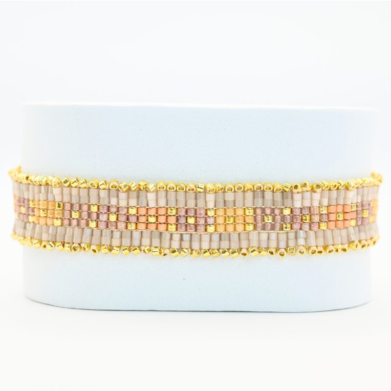"cette manchette raffinée se compose de 7 rangs de perles, alternant élégance et éclat. Deux rangs extérieurs de perles dorées encadrent des perles nude, tandis que trois rangs centraux dans les tons roses apportent une touche délicate et féminine. . Bijou seul, Crédit GEMITY"