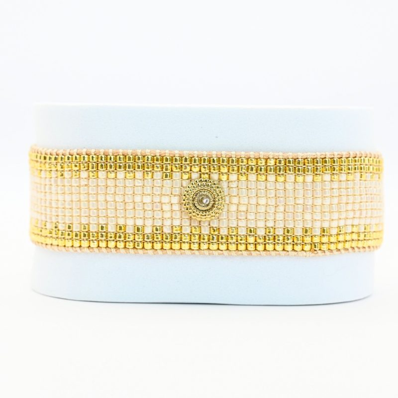 cette grande manchette élégante se compose de 12 rangs de perles dorées et nude, offrant un mélange subtil de luminosité et de douceur. L'ornement cercle au centre ajoute une touche contemporaine et raffinée, créant un look moderne et intemporel.. Bijou seul, Crédit GEMITY
