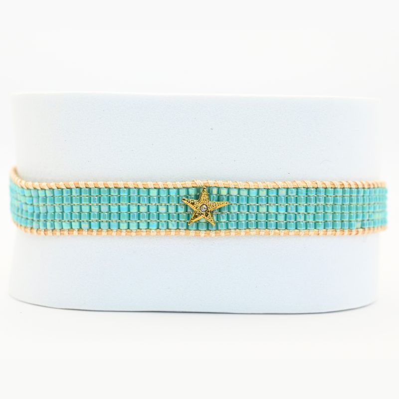 inspirée des nuances apaisantes de l’océan, cette petite manchette se compose de 5 rangs de perles bleues lagon. Son ornement étoile avec un zircon disposé au centre du bracelet apporte une touche lumineuse. . Bijou seul, Crédit GEMITY