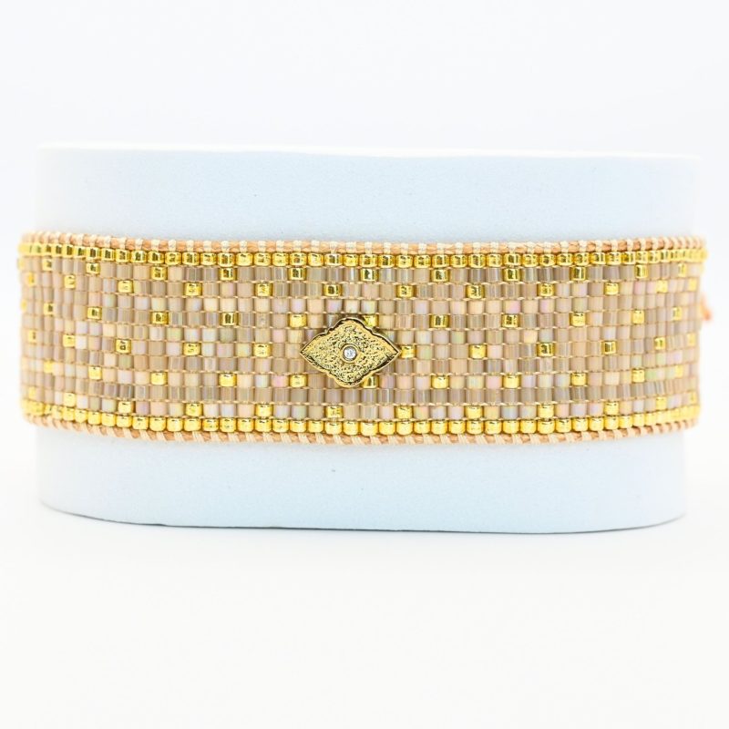 élégante et raffinée, cette grande manchette se compose de 12 rangs de perles dorées et nude, créant une texture luxueuse et un contraste subtil. L'ornement losange au centre ajoute une touche géométrique et moderne, apportant une touche d'originalité et de sophistication à ce bijou.. Bijou seul, Crédit GEMITY