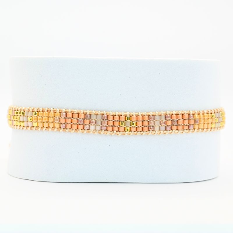 cette mini manchette élégante est composée de 3 rangs de perles nude, dorées et roses poudrées, créant un design doux et féminin. . Bijou seul, Crédit GEMITY