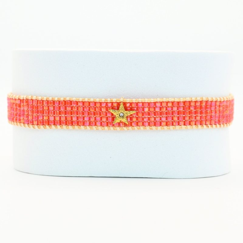 ajoutez une touche de fraîcheur et de lumière à votre poignet avec cette petite manchette élégante. Composée de 5 rangs de perles roses orangées, elle diffuse une couleur douce et chaleureuse. L'ornement étoile en son centre apporte une note délicate et scintillante.. Bijou seul, Crédit GEMITY