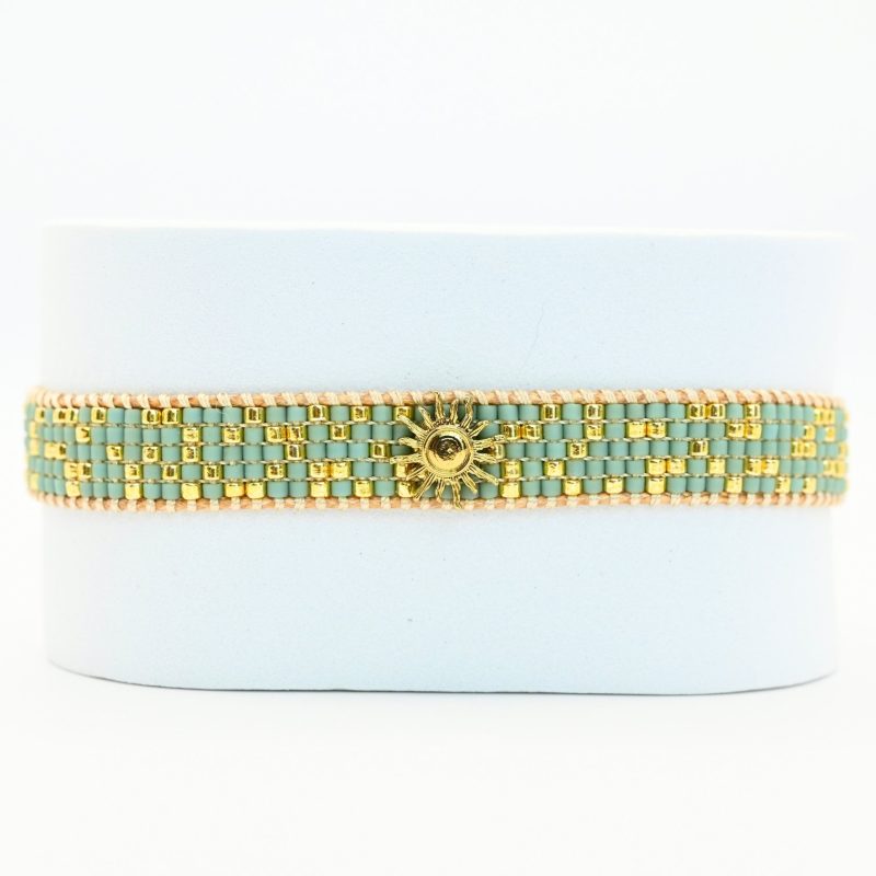 sublimez votre poignet avec cette petite manchette délicate, composée de 5 rangs de perles dorées et vert d'eau qui apportent une touche fraîche et lumineuse. L'ornement soleil au centre ajoute une note rayonnante et éclatante, idéale pour apporter une touche d'élégance à vos tenues.. Bijou seul, Crédit GEMITY