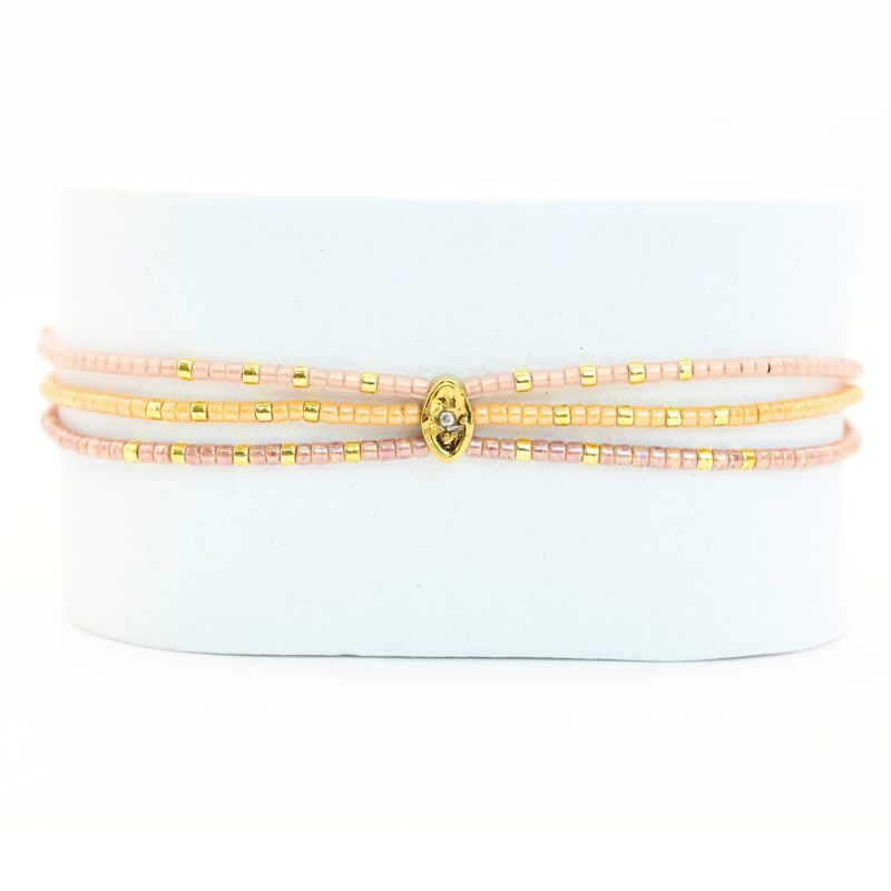 ce bracelet fin à 3 rangs regroupe des perles dorées et nude, créant un effet raffiné et élégant. L'ornement central rassemble les rangs pour un look harmonieux et sophistiqué. . Bijou seul, Crédit GEMITY