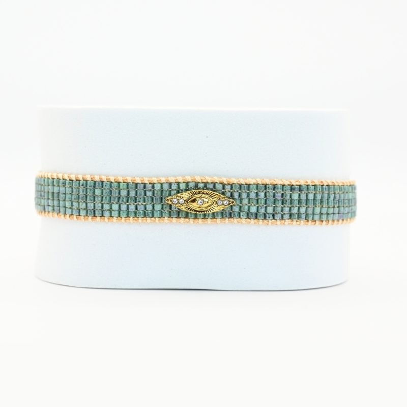 apportez une touche de mystère et de style à votre poignet avec cette petite manchette élégante, composée de 5 rangs de perles vertes vibrantes. L'ornement œil en son centre ajoute une dimension symbolique et unique à ce bijou.. Bijou seul, Crédit GEMITY
