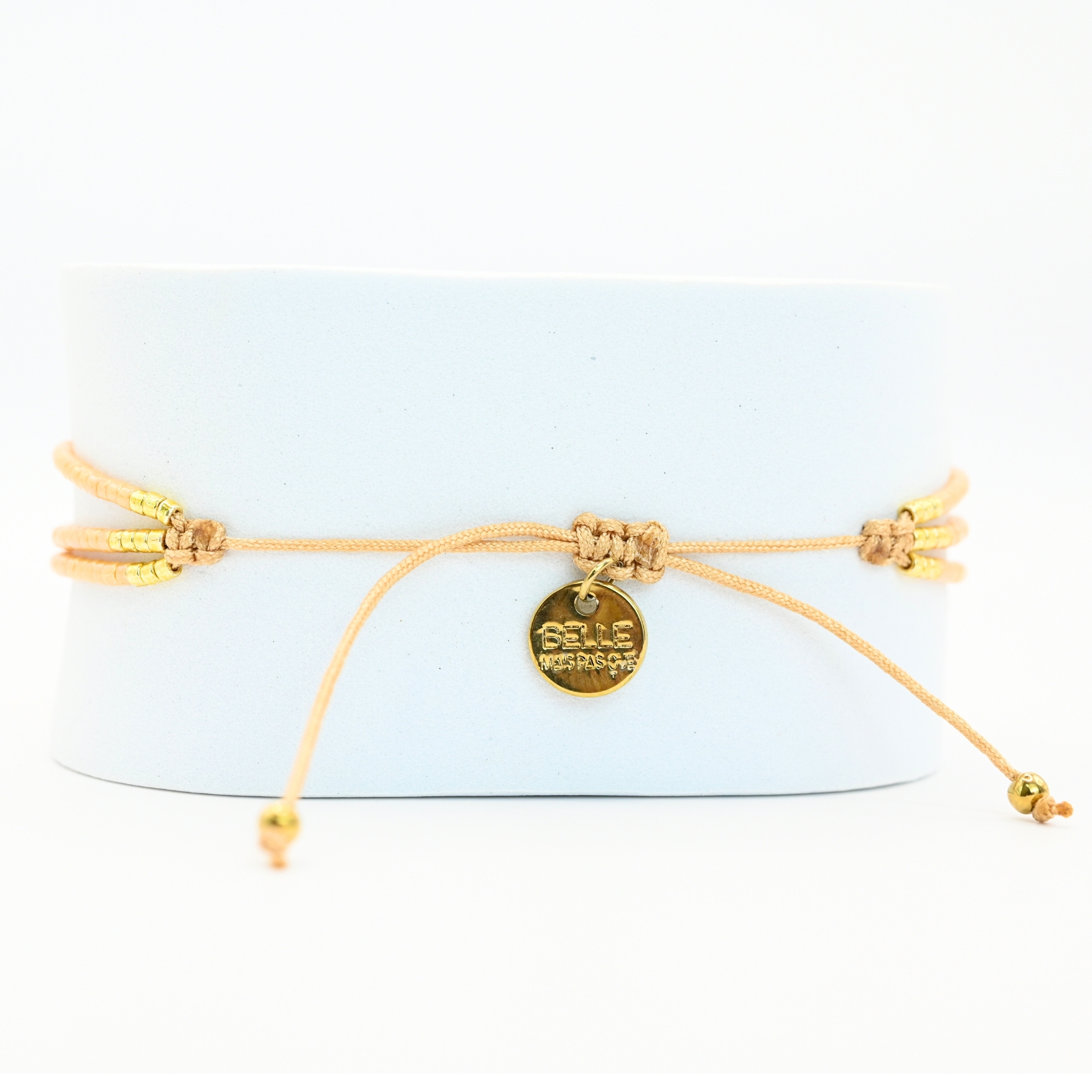 ce bracelet fin à 3 rangs associe des perles dorées et nude, créant un look élégant et discret. Les rangs sont réunis par deux ornements délicats, ajoutant une touche supplémentaire de raffinement et de structure. . Bijou seul, Crédit GEMITY