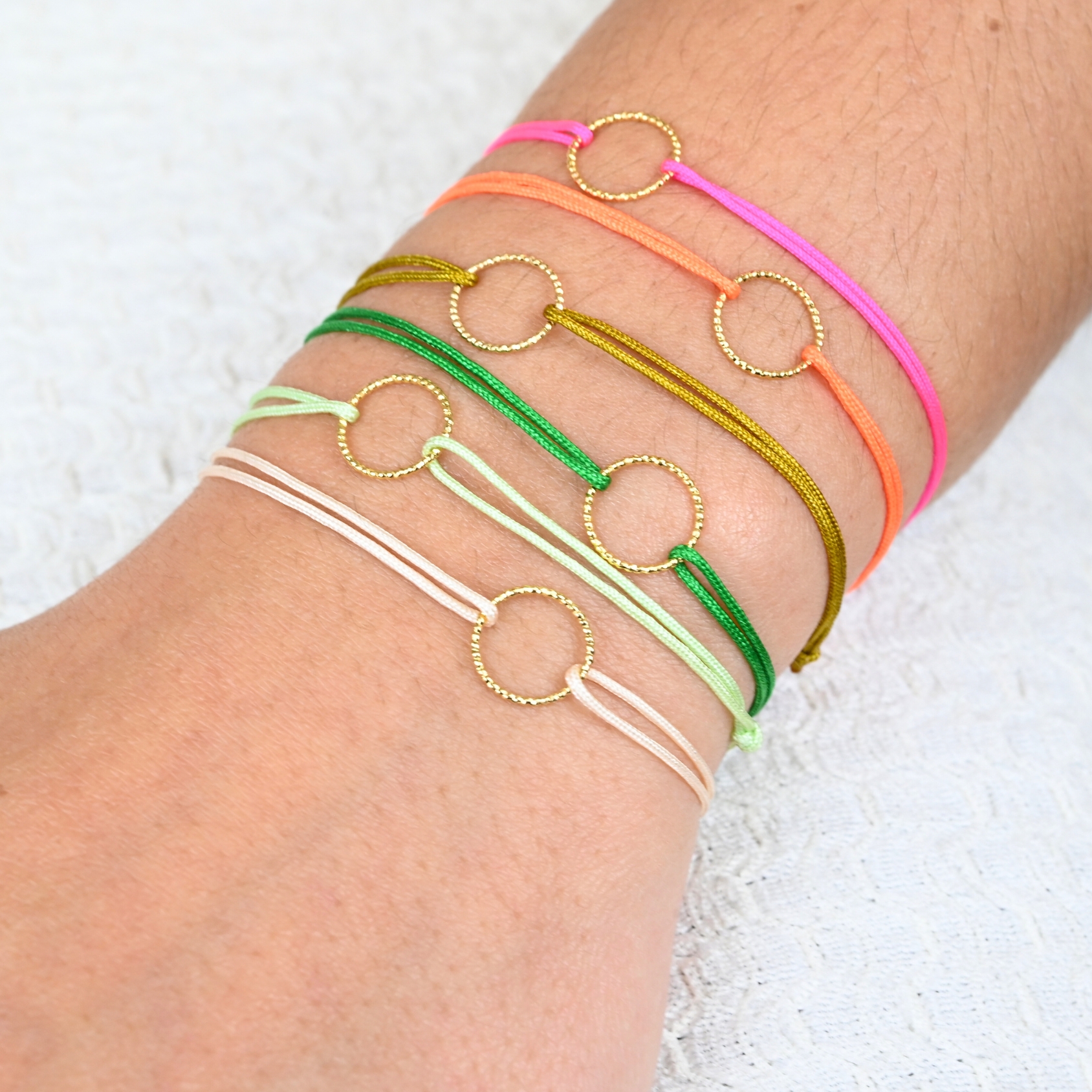 Bracelets de l'amitié, vendu par deux. Cercle en plaqué or (3 microns). Le bracelet est en tissu et vous retrouvez en son centre un magnifique cercle en plaqué or. . Bijou porté, Crédit GEMITY.