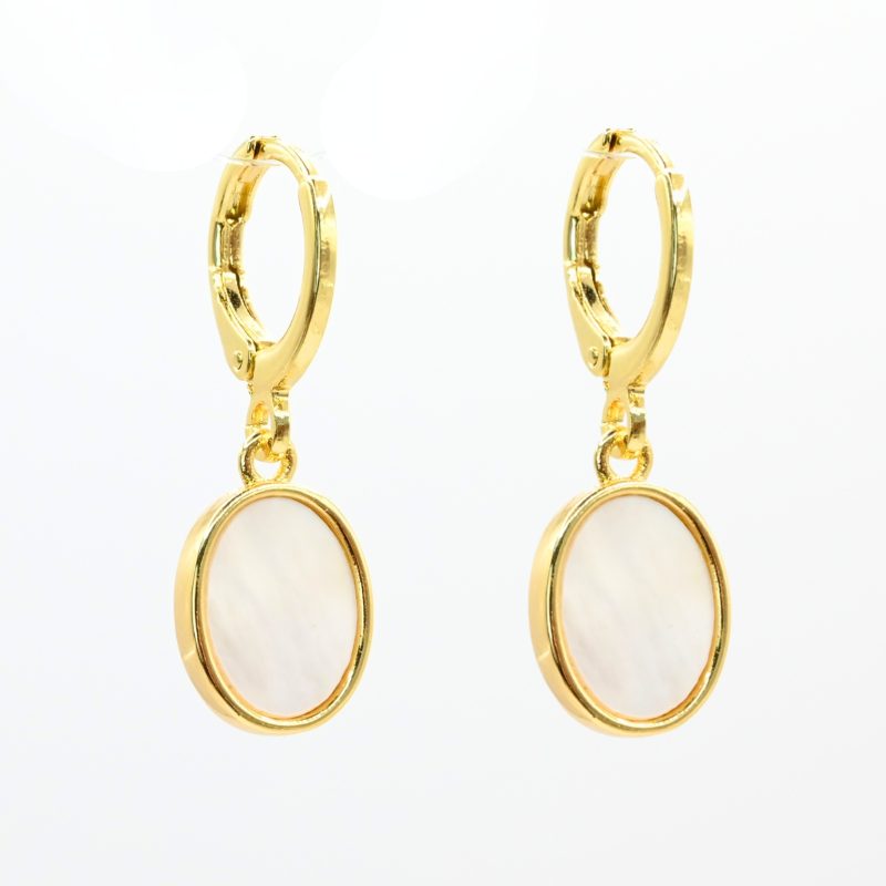 "Boucles d’oreilles dormeuses avec une nacre découpée en ovale entourée par le métal doré à l’or fin. La nacre naturelle est mise en valeur de manière subtile mais envoûtante, avec ses irisations délicates qui scintillent à la lumière. Taille du pendant : 12 mm. Bijou seul, Crédit GEMITY"