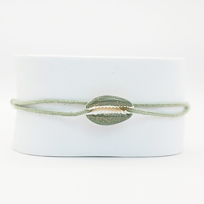 "Véritable cauri émaillé (longueur ≈ 1,5 cm) de la même couleur que le cordon. Lien cordon en coton ajustable, convient pour des poignets de 14 à 19 cm.. Bijou seul, Crédit GEMITY"