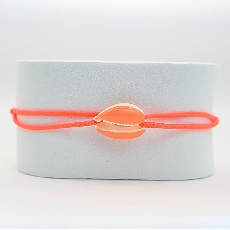 "Véritable cauri émaillé (longueur ≈ 1,5 cm) de la même couleur que le cordon. Lien cordon en coton ajustable, convient pour des poignets de 14 à 19 cm.. Bijou seul, Crédit GEMITY"