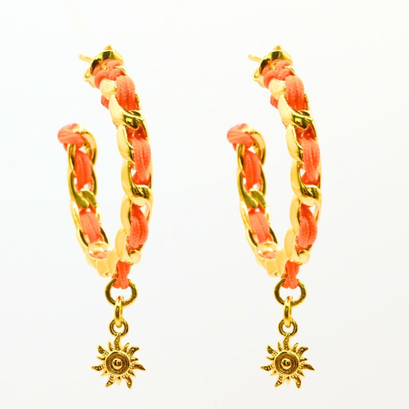 "Les boucles d'oreilles Monsens, inspirées de la collection Couture, où l'on retrouve un célèbre charm et une couleur dominante dans la maille. Taille : 27 mm de diamètre Composition : plaqué or et fil de coton.. Bijou seul, Crédit GEMITY"