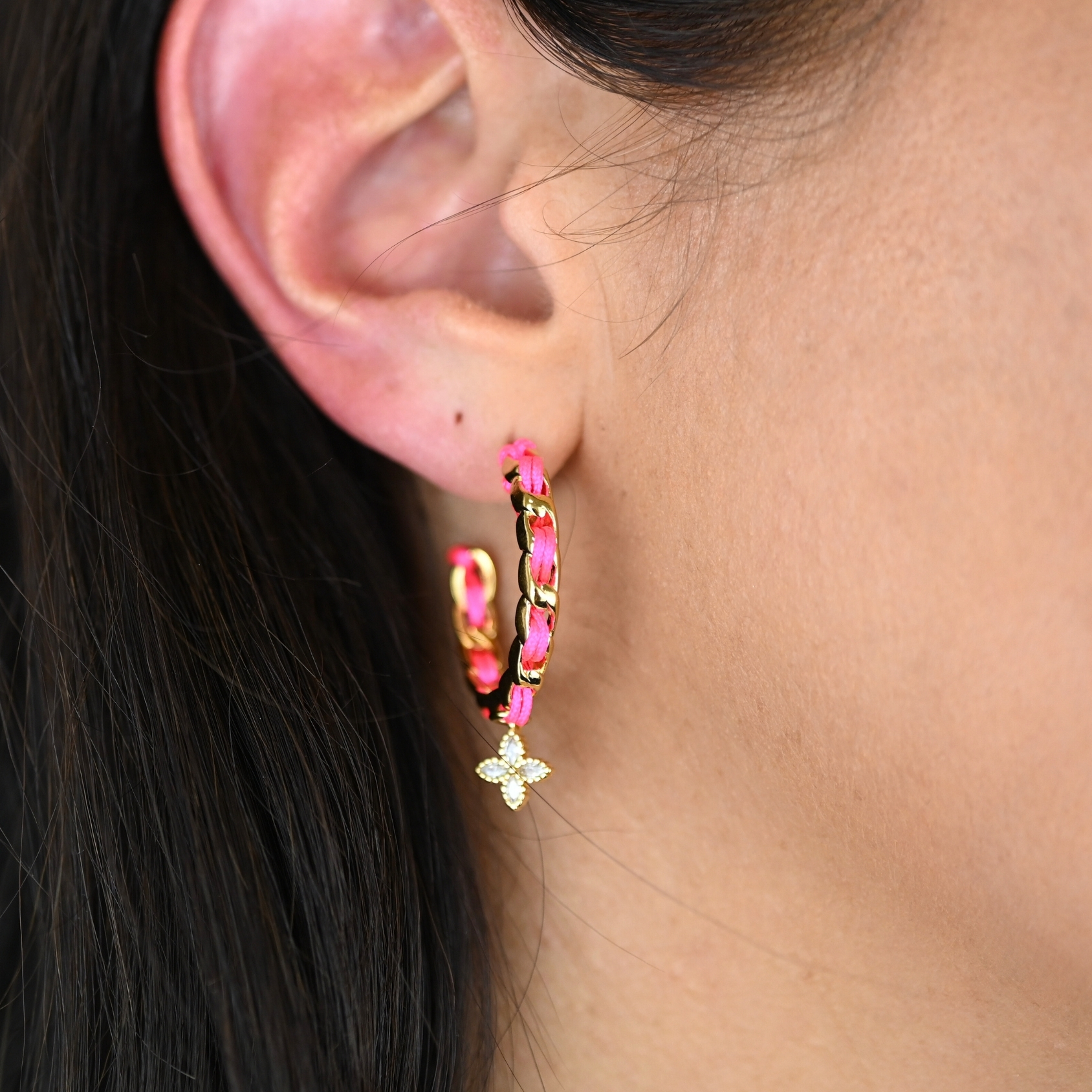 "Les boucles d'oreilles Monsens, inspirées de la collection Couture, où l'on retrouve un célèbre charm et une couleur dominante dans la maille. Taille : 27 mm de diamètre Composition : plaqué or et fil de coton. . Bijou porté, Crédit GEMITY."